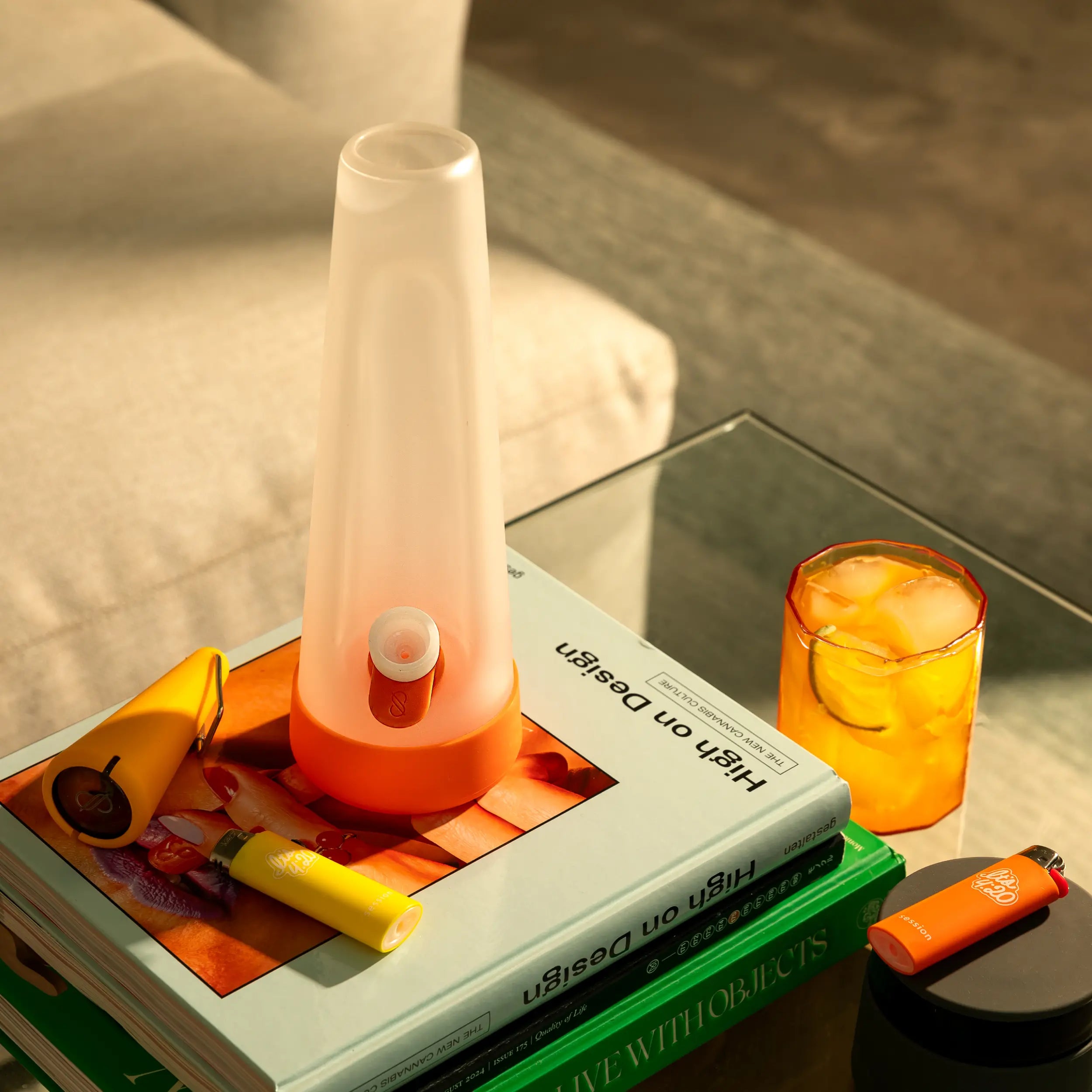 Frosted orange bong on books with lighters and a citrus drink, part of the Fall Harvest Collection — up to 30% off — mobile ratio image