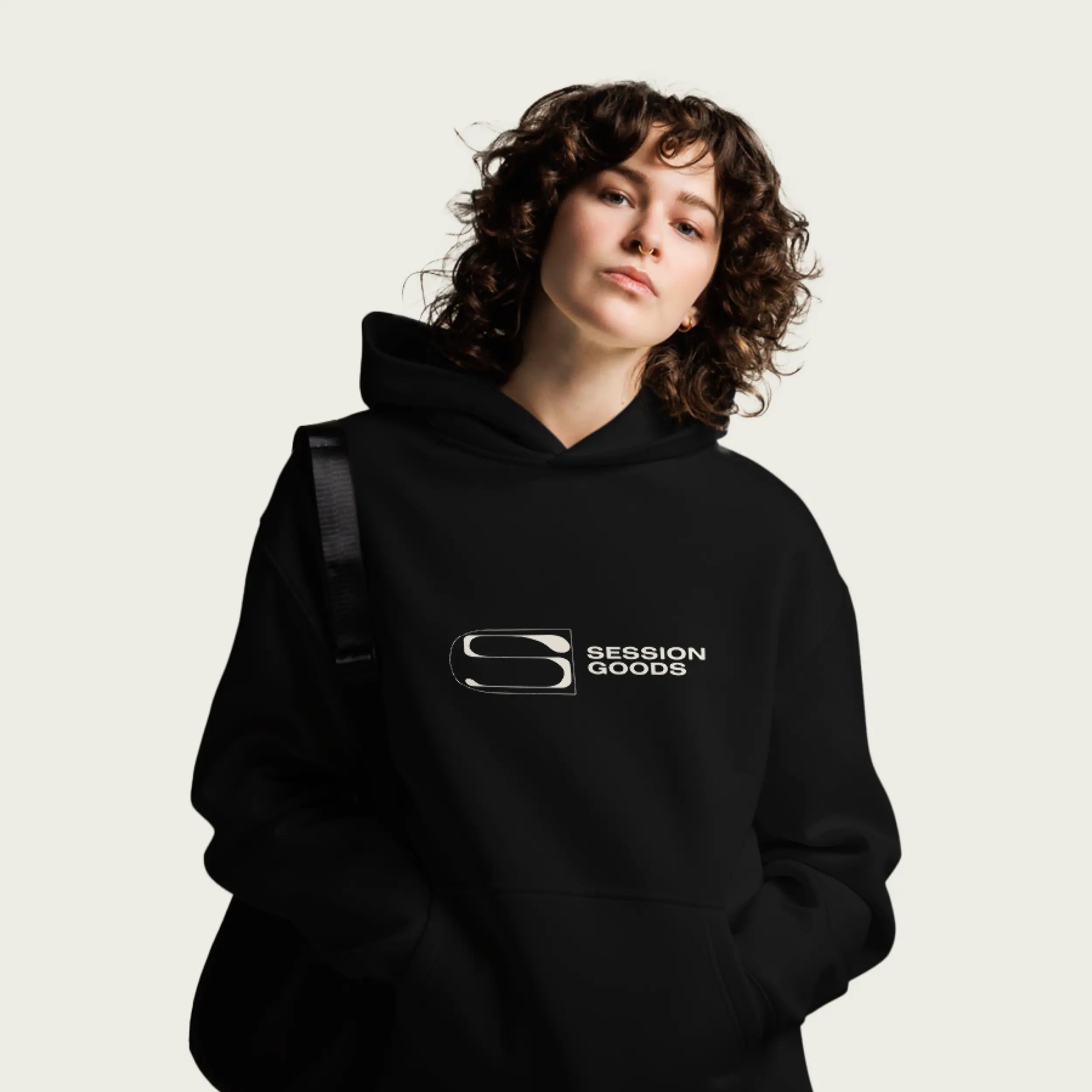 Person wearing a black hoodie with 'Session Goods' Normform logo on a plain background