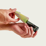 Model holding the Green Aura portable pipe against a neutral studio backdrop, showcasing its compact design and translucent green tones