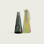 Modern portable pipe in Green Aura colorway, with a glow-in-the-dark silicone sleeve, shown in a clean studio setting on a black background gif that flips to a clean studio setting on a white background