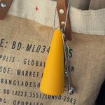 Yellow Paradise Session Goods Portable Pipe with keychain holder clipped to a canvas tote bag with leather strap, holding a small stainless steel 1/8 teaspoon.
