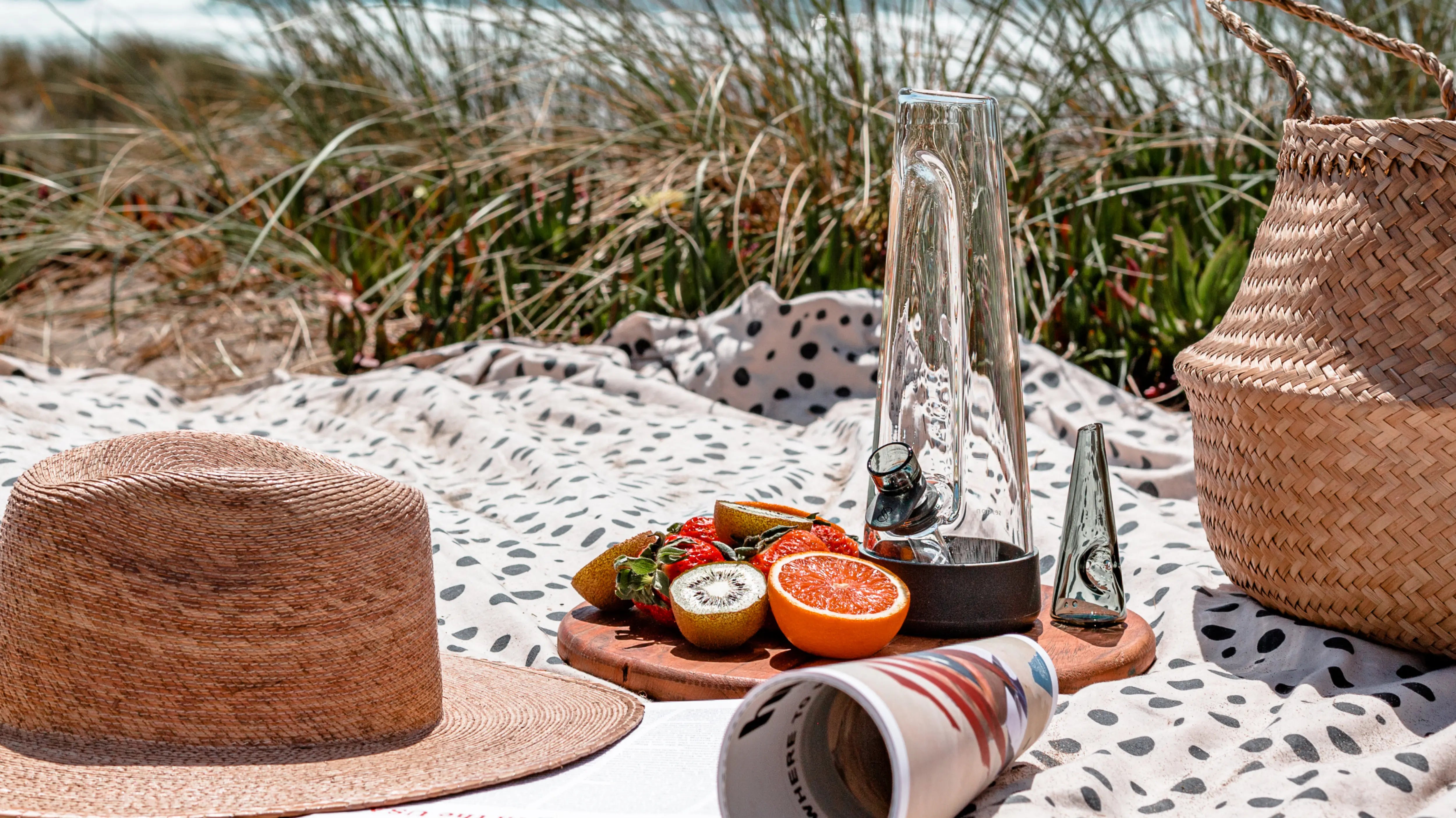 Charcoal Bong and pipe on a beach blanket with fresh fruit in the tall seagrass