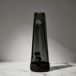 Tall, dark-colored glass vase on a marble surface with a neutral background