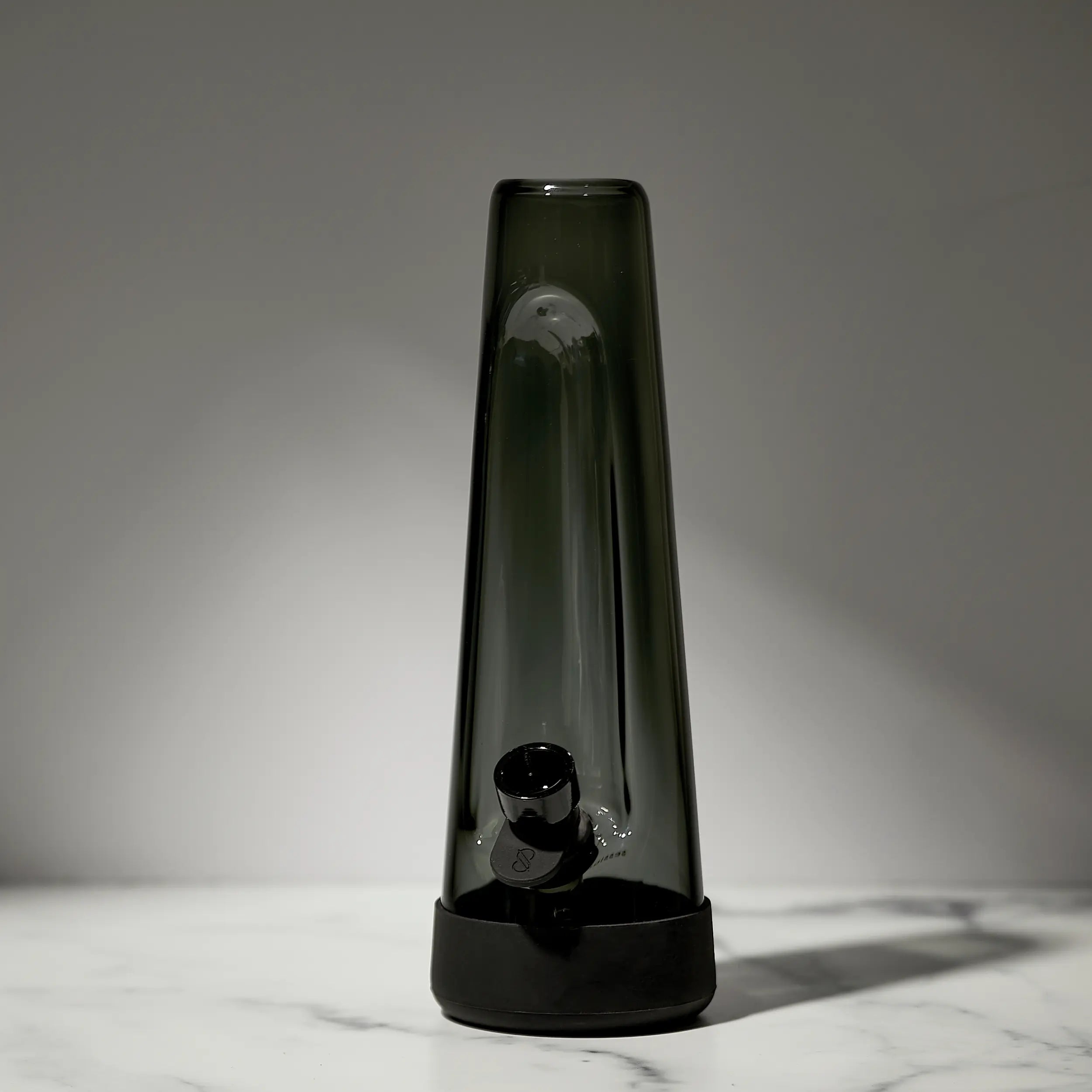 Tall, dark-colored glass vase on a marble surface with a neutral background