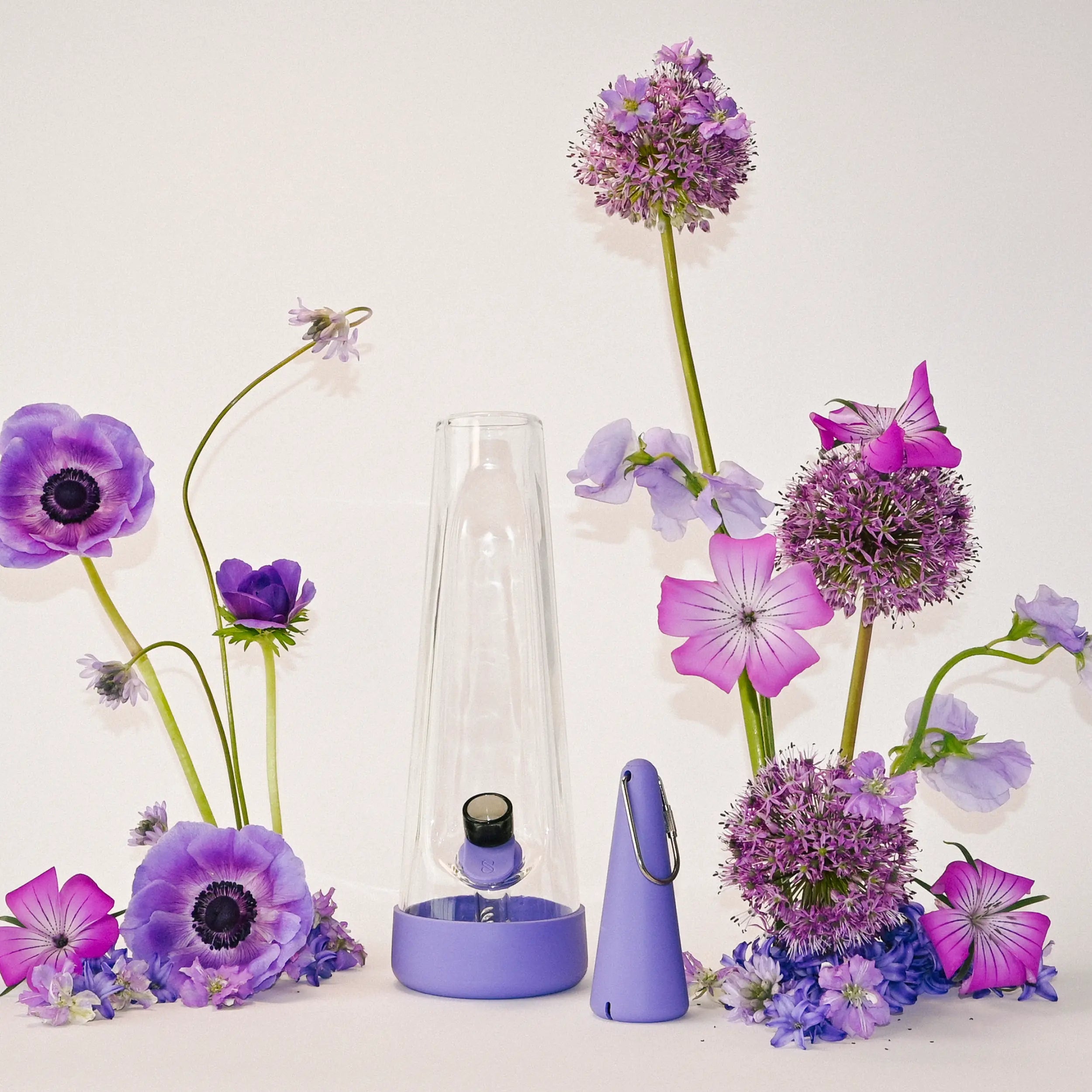 Session Goods Valentine's Day sale featuring the designer glass bong and travel pipe in Moonlight Purple, surrounded by a floral arrangement of purple anemones and wildflowers.