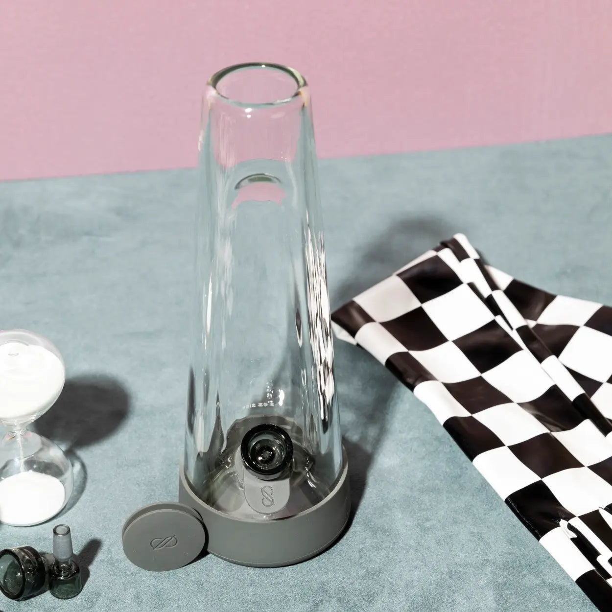 Goods modern glass water pipe with gray silicone base and extra bowl pieces, styled with a checkered racing flag and hourglass for the Winter Games collection.