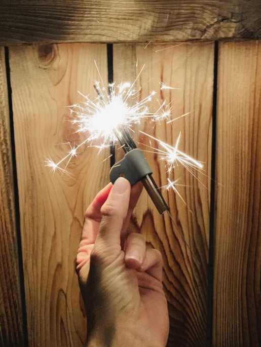holding a session goods minimal designed one-hitter with a sparkler firework in held in hand over a wood fence backdrop