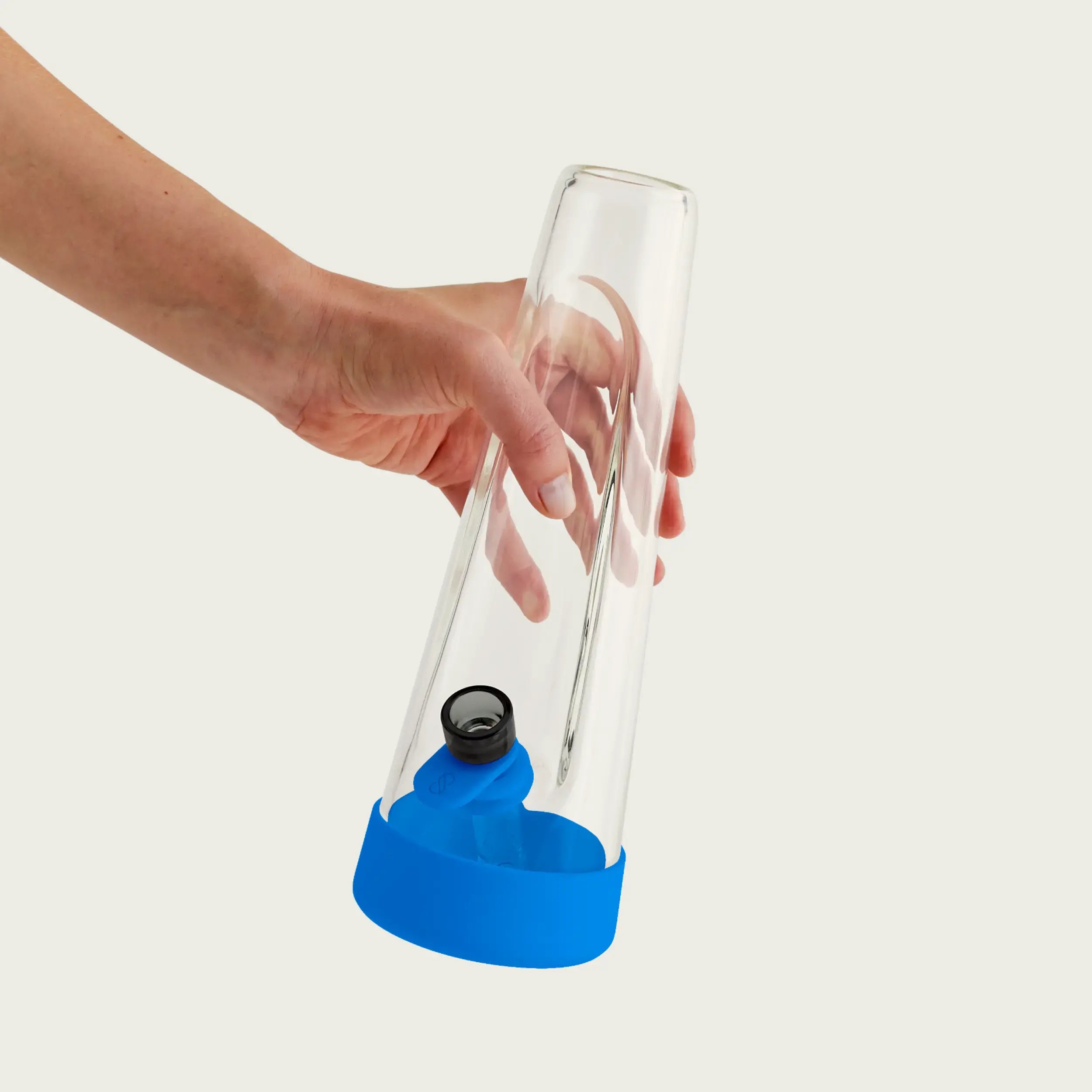 A hand holds the clear glass Session Bong by its neck, showcasing the vibrant Cyan Blue silicone protective footer and the coordinating blue pull tab attached to the glass bowl.
