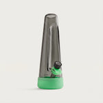A modern, tapered dark glass water pipe with mint green silicone base cover and bowl grip against a plain light gray background.