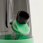 Close-up view of a dark glass water pipe bowl with a mint green silicone tab and protective base.