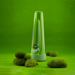 Session Goods Grass Bong on a bright green backdrop with moss accents, blending nature-inspired design with modern aesthetics
