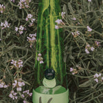 Session Goods Designer Series Grass Bong nestled in wildflowers, highlighting translucent green glass and matching silicone base