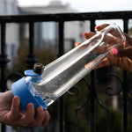 A lifestyle shot of two people sharing a moment on an urban balcony, holding the Cyan Blue Session Bong against a backdrop of city architecture.