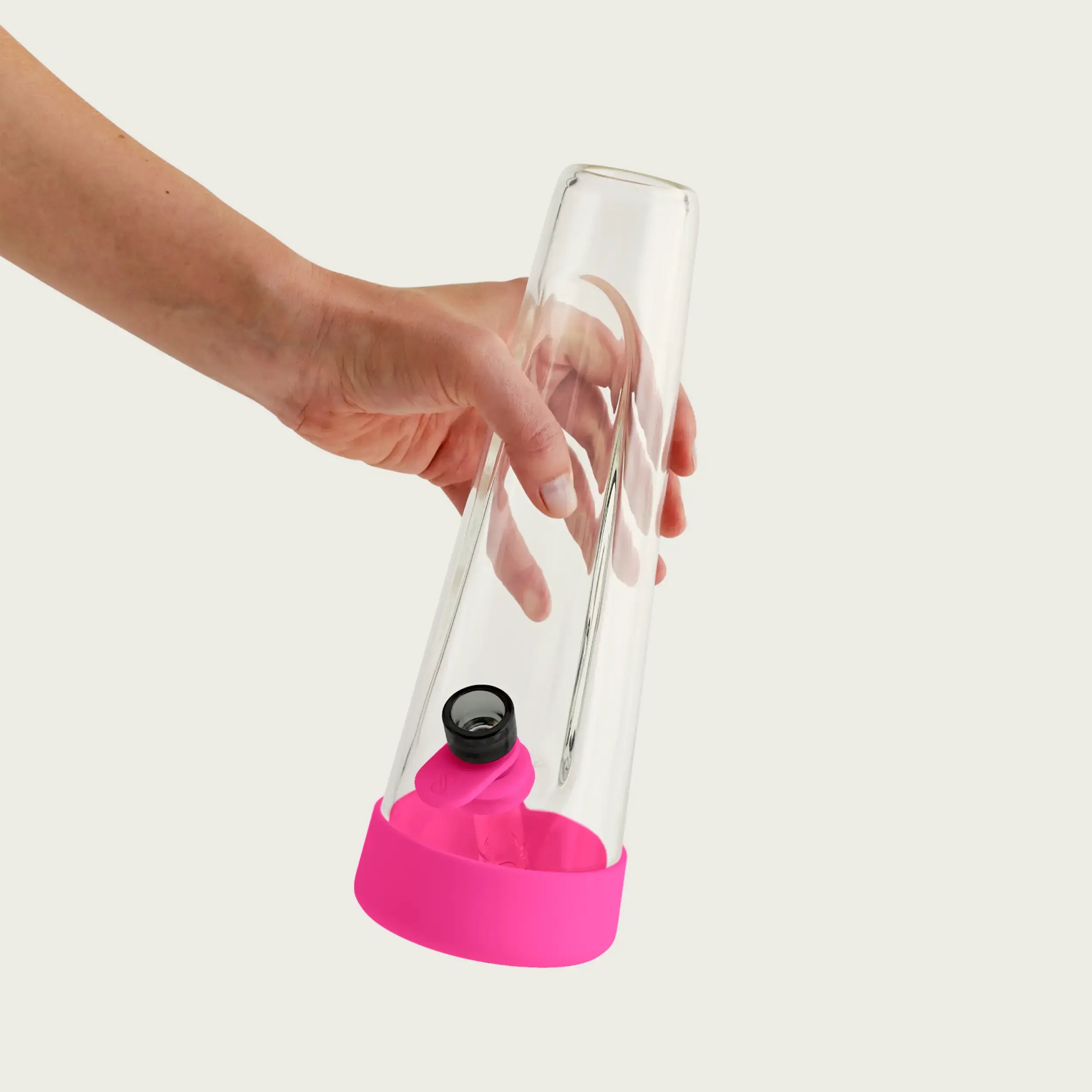 A dynamic view of a hand holding the clear glass Session Bong by its neck, highlighting the vibrant Magenta Pink silicone footer and the ergonomic pull tab on the bowl.