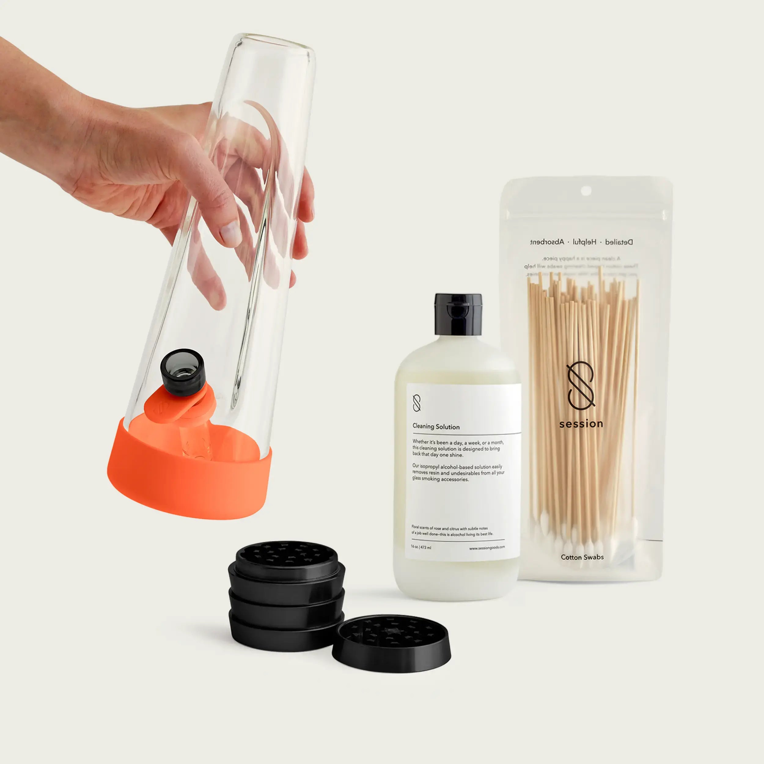 Vibrant Horizon Orange Session Goods starter bundle featuring an orange-accented glass bong and a four-piece metal grinder on a light wood table.