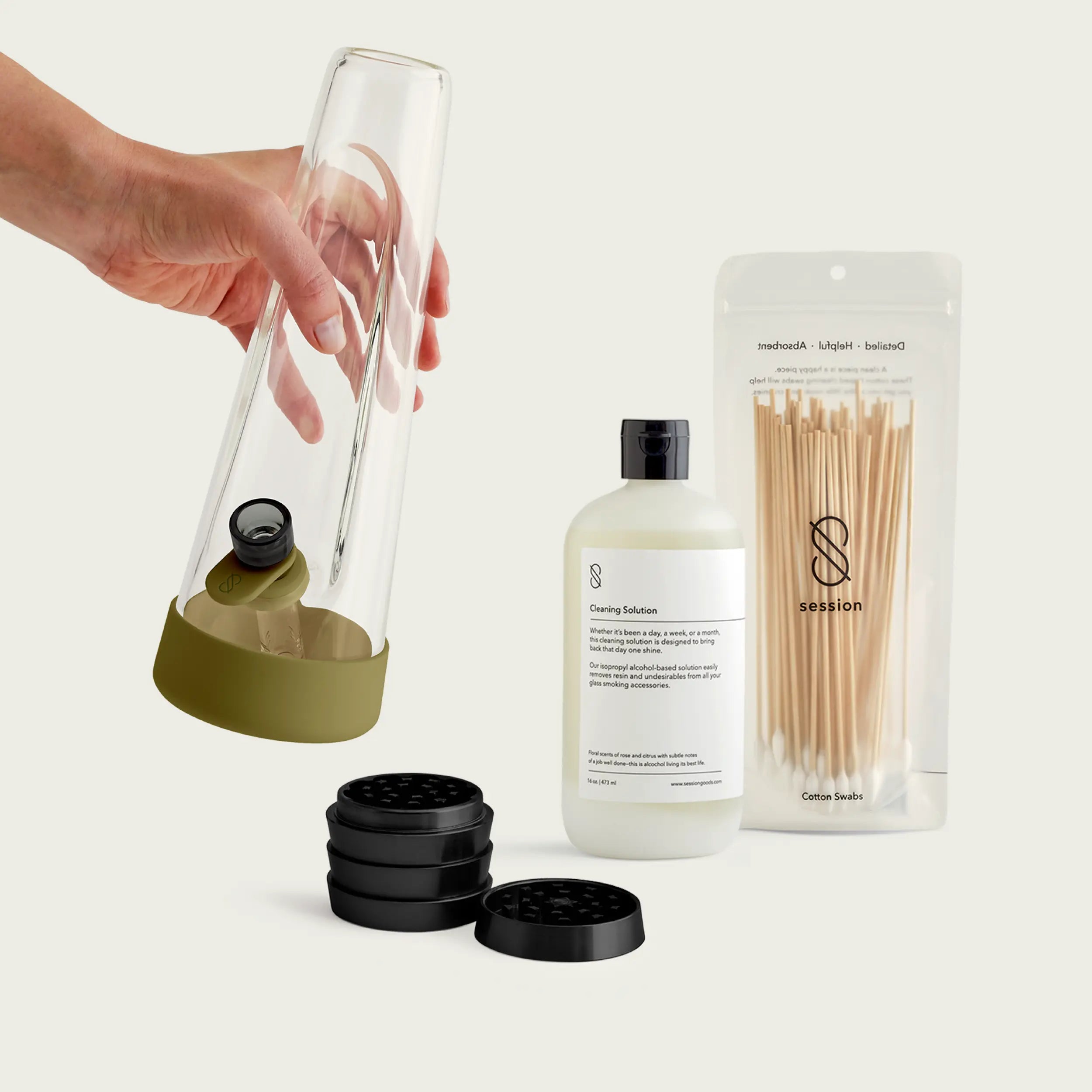 An Olive Green Session Goods starter kit featuring a forest-green accented glass bong, a matte black grinder, and professional cleaning solution in a studio image background