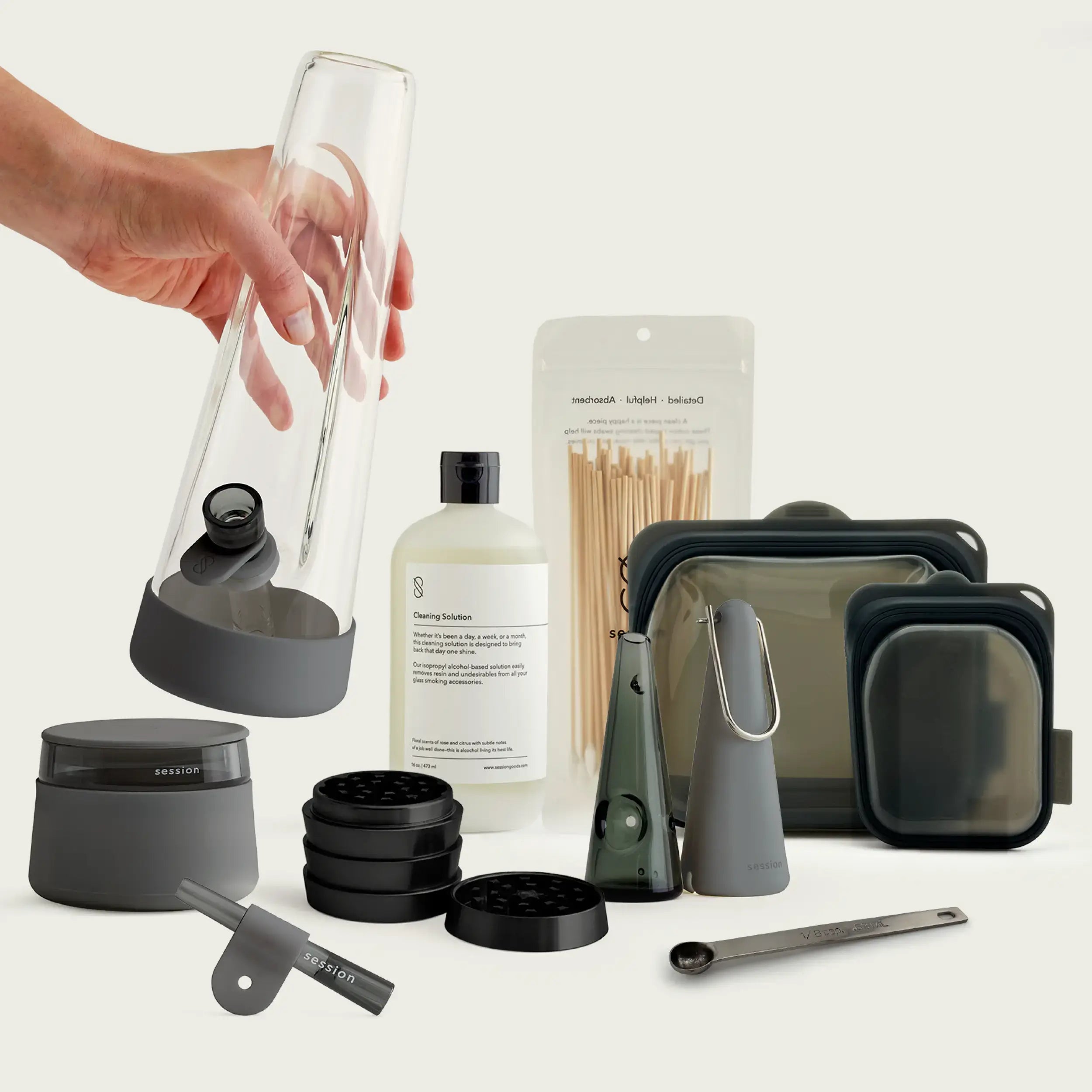 A complete collection of Session Goods glass smoking accessories in Charcoal Gray, including a minimalist 4mm borosilicate bong, hand pipe, stash jar, and cleaning kit on a modern shelf.