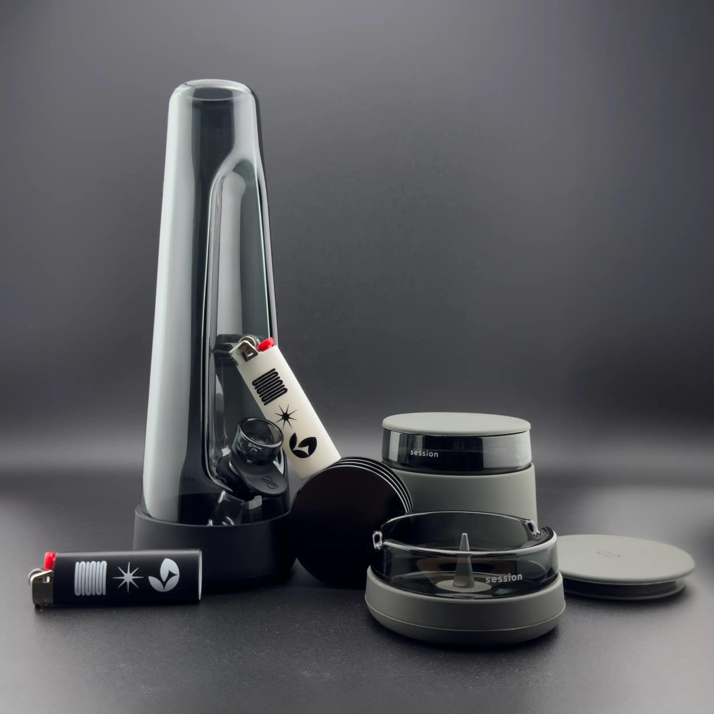 Session Goods Ultimate Bong Bundle in Ash, featuring the designer black glass bong, matching debowler ashtray, stash jar, and black and white designer lighters.