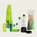 Session Goods Designer Series Ultimate Bundle in green tones, featuring a translucent green bong, matching silicone accessories, two ‘Do nothing.’ branded lighters, a clear water bottle labeled ‘Dry Mouth Erase.’, a sleek one-hitter pipe with cone sleeve, a black four-piece grinder, and two stash pods with green caps—all arranged on a neutral background.