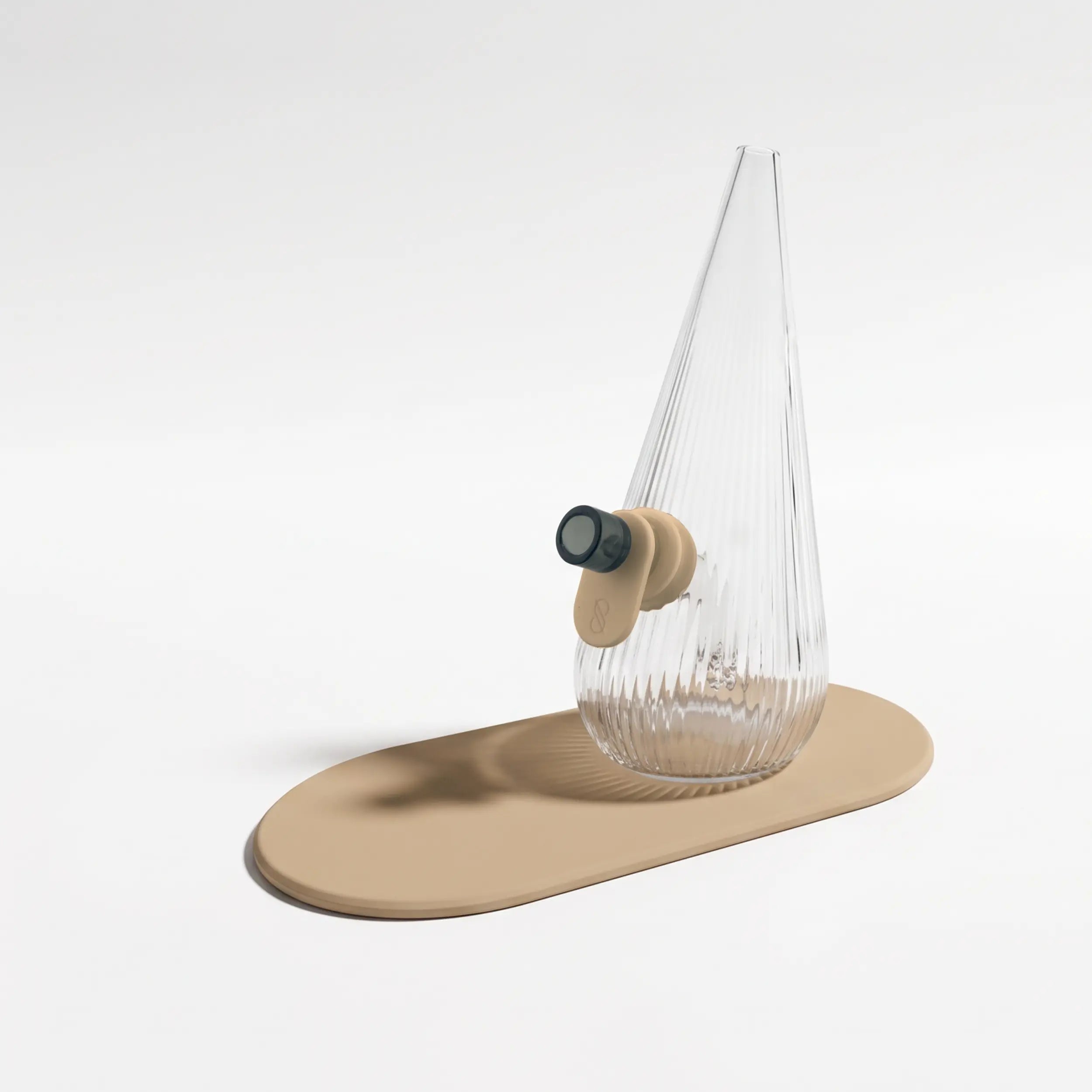 Session Goods ribbed clear glass Drop Bubbler featuring a sand tan silicone grommet tab and matching silicone mat, fitted with a dark glass bowl piece.