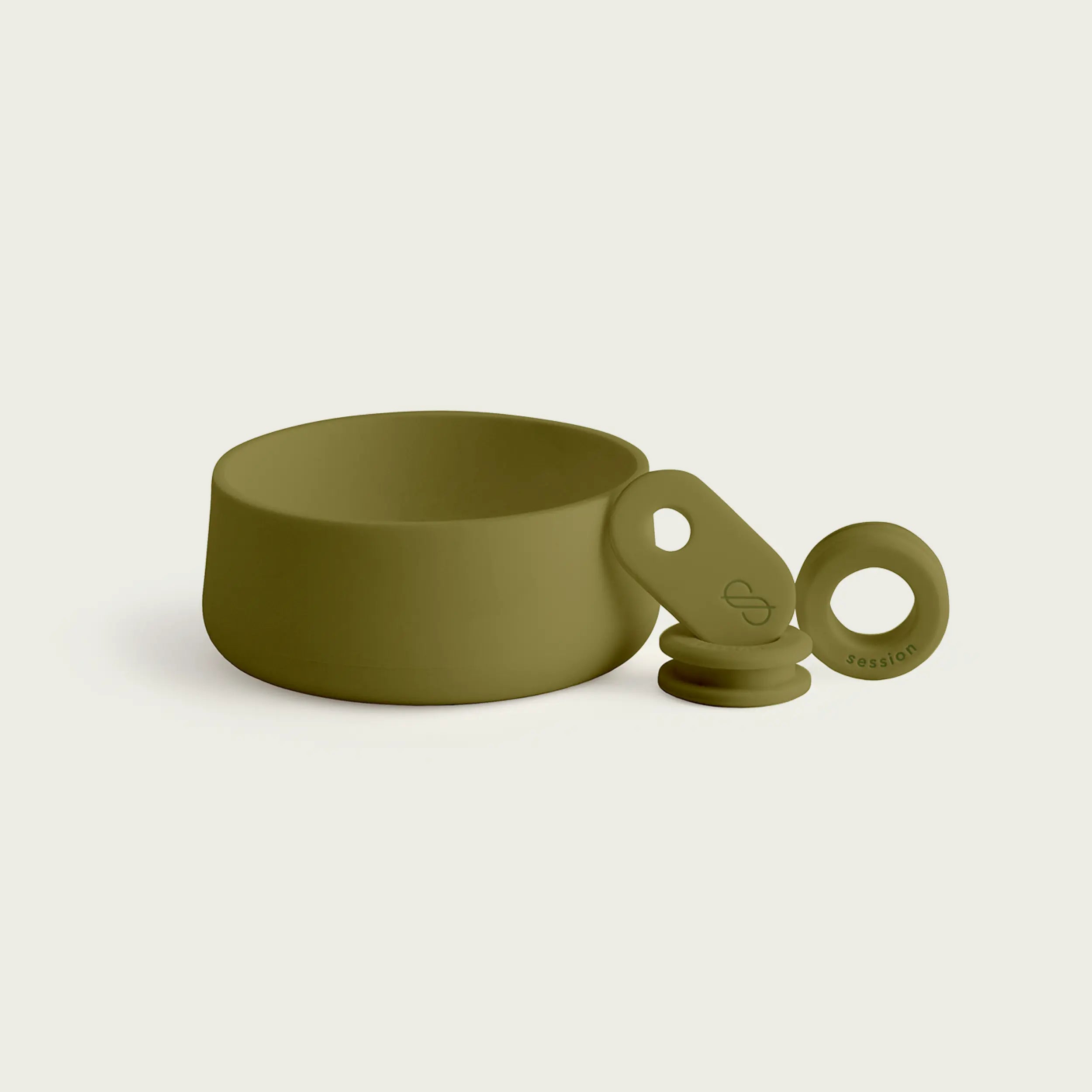 A studio product shot of a Session Goods silicone accessory set in olive green. The set includes a circular protective footer, a tabbed bowl sleeve with a debossed logo, and a small grommet, all displayed against a neutral background.