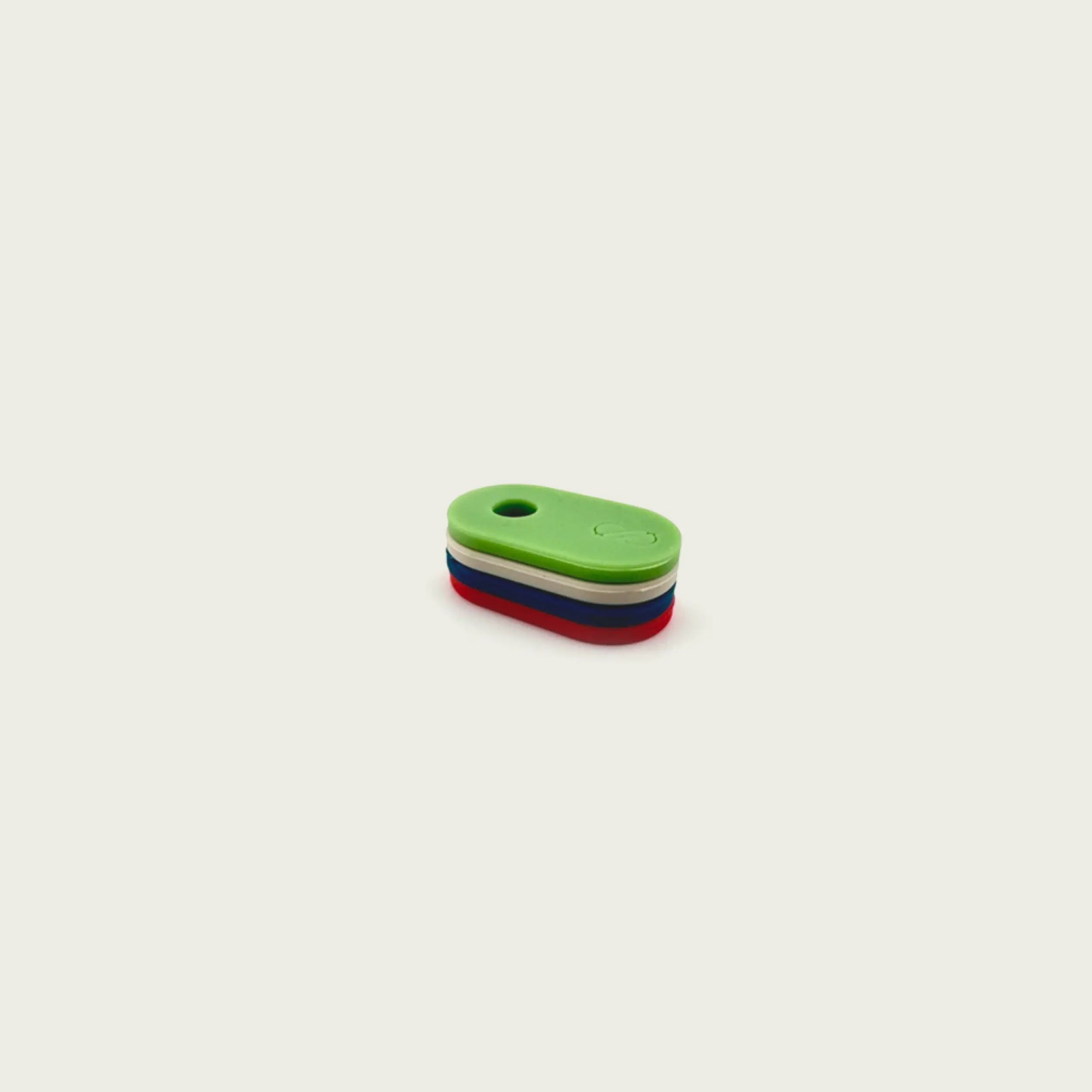 Stack of four silicone tabs in red, navy blue, sand, and green for Session Goods bongs, shown from a side view