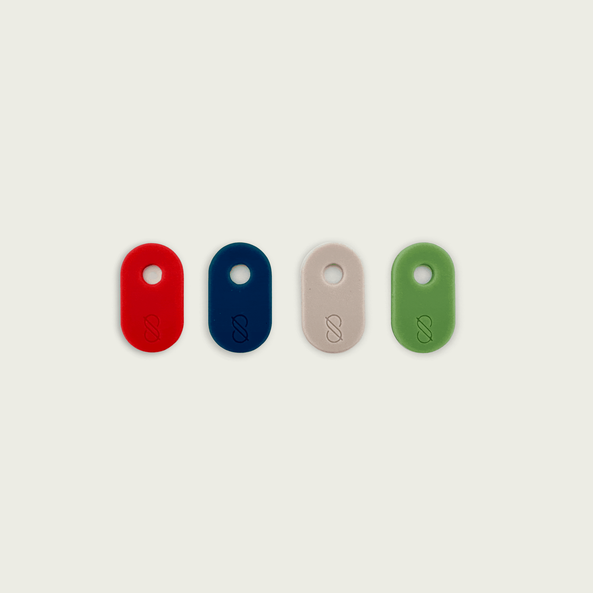 Colorful silicone tabs for Session Goods bongs laid flat in a mystery color pack, each with a hole for attachment and an embossed logo