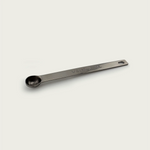 Stainless steel 1/8 teaspoon measuring spoon with engraved 0.63 mL marking, shown at an angled side perspective on a light background.