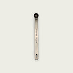 Stainless steel 1/8 teaspoon measuring spoon with engraved measurement markings, photographed from above on a light background.